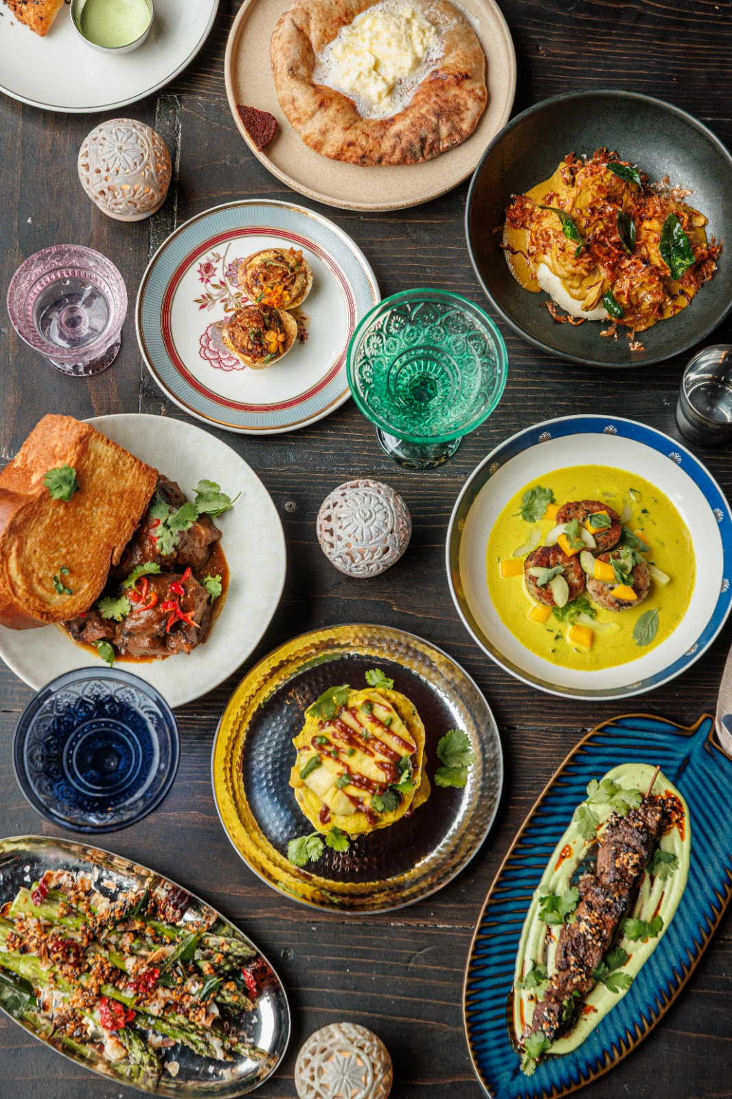 An overhead spread of Dravida signature dishes: kebabs, deviled eggs, curries, and breads on the table